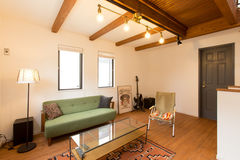 Esempio di un piccolo soggiorno etnico aperto con pareti bianche, pavimento in legno massello medio e pavimento marrone