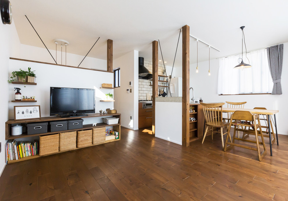 Imagen de salón abierto campestre con paredes blancas, suelo de madera oscura, televisor independiente y suelo marrón