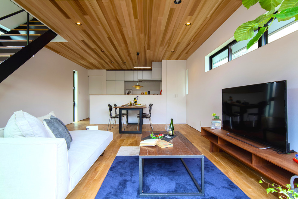 Foto di un soggiorno design di medie dimensioni e aperto con pareti bianche, pavimento in legno massello medio, TV autoportante e pavimento marrone