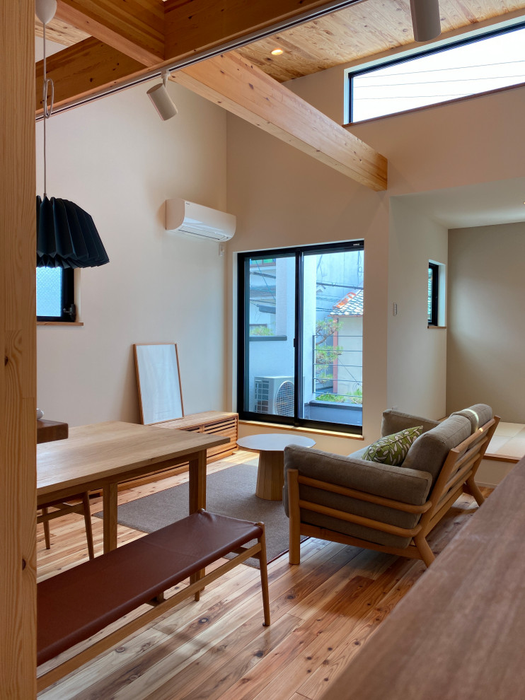 Стильный дизайн: маленькая открытая гостиная комната в восточном стиле с белыми стенами, светлым паркетным полом, отдельно стоящим телевизором и деревянным потолком для на участке и в саду - последний тренд