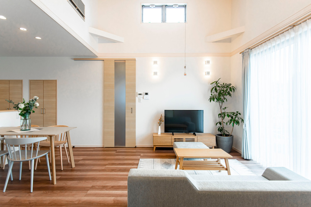 Immagine di un soggiorno minimal aperto con pareti bianche, pavimento in legno massello medio, TV autoportante e pavimento marrone