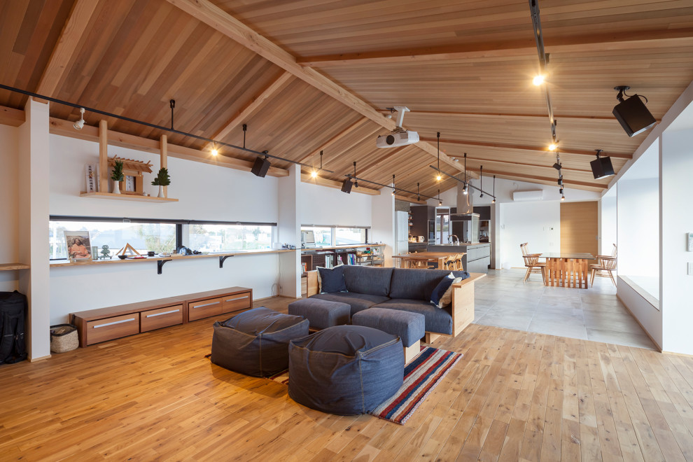 Cette image montre un salon design ouvert avec un mur blanc, un sol en bois brun, un sol marron et un plafond voûté.