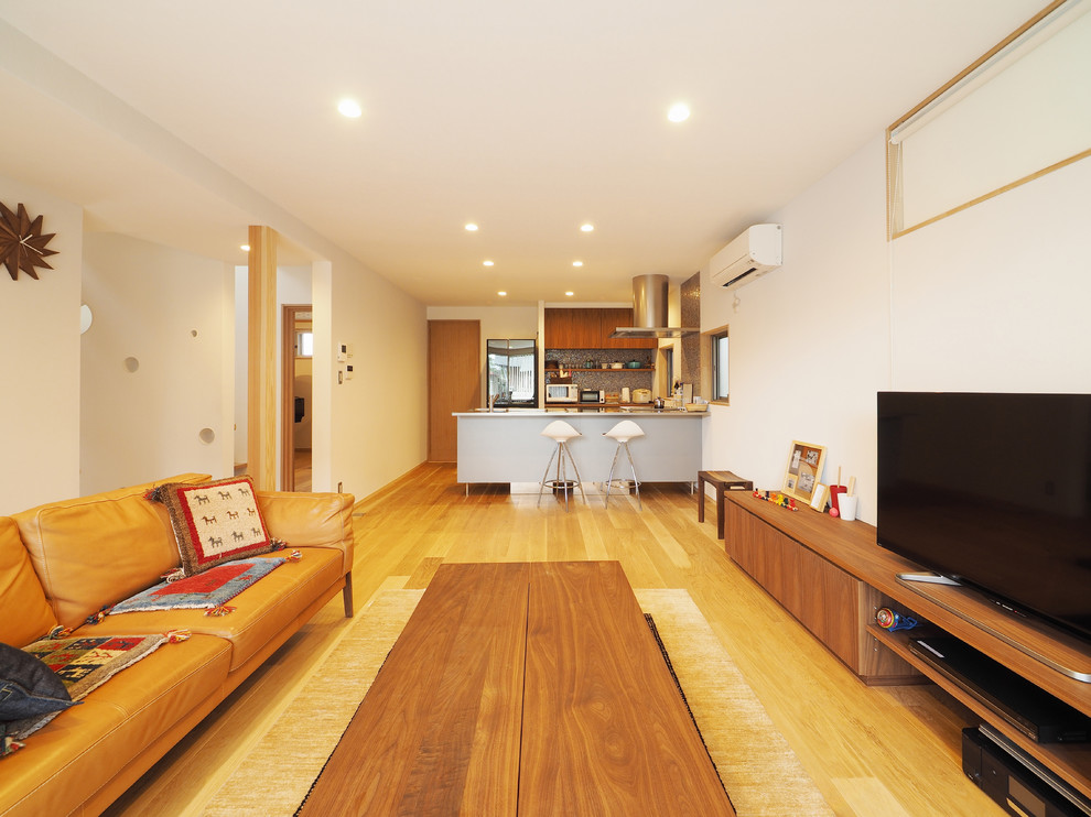 Aménagement d'un salon contemporain avec un mur blanc, un sol en bois brun, un téléviseur indépendant et un sol marron.