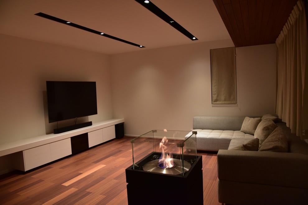 Esempio di un soggiorno design aperto con pareti bianche, parquet scuro e TV a parete