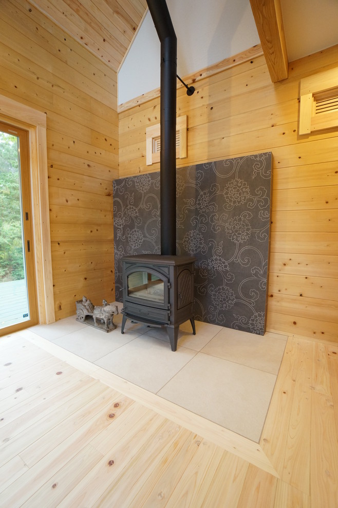 На фото: гостиная комната с бежевыми стенами, светлым паркетным полом, печью-буржуйкой и деревянными стенами с