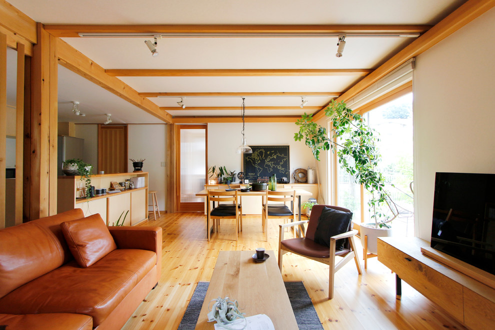 Foto di un soggiorno etnico aperto con pareti bianche, pavimento in legno massello medio, TV autoportante e pavimento marrone
