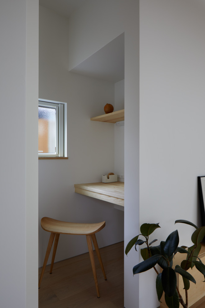 Kleines Nordisches Arbeitszimmer ohne Kamin mit Arbeitsplatz, weißer Wandfarbe, hellem Holzboden, Einbau-Schreibtisch, Tapetendecke und Tapetenwänden in Sonstige