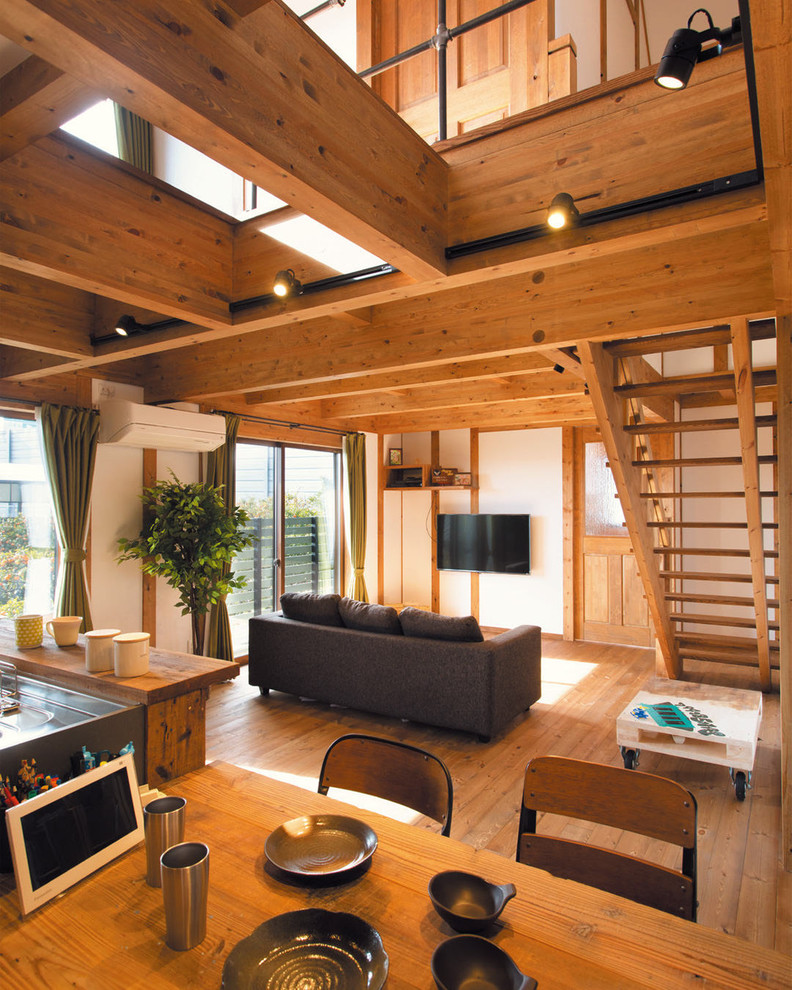 Foto de salón abierto de estilo de casa de campo con paredes blancas, suelo de madera clara, televisor colgado en la pared y suelo marrón