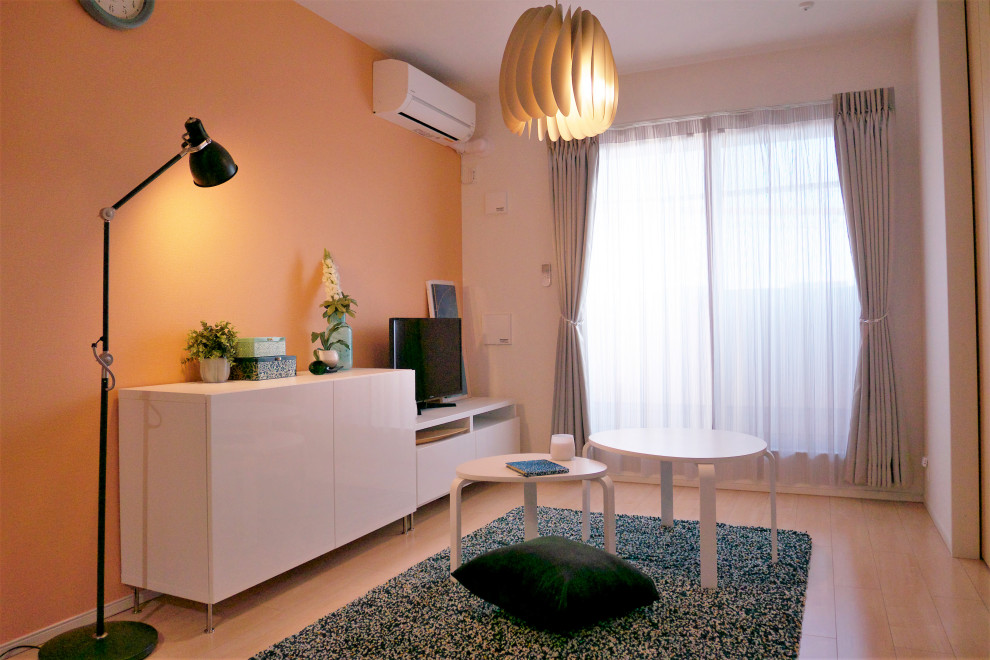 Источник вдохновения для домашнего уюта: маленькая открытая гостиная комната в скандинавском стиле с оранжевыми стенами, полом из фанеры и отдельно стоящим телевизором для на участке и в саду