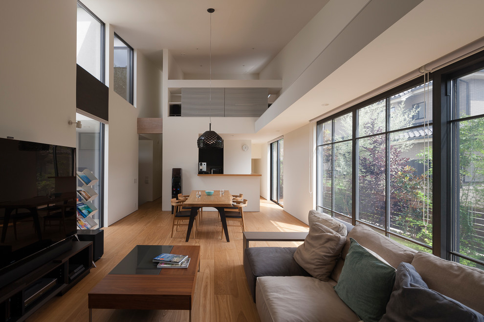 Offenes Modernes Wohnzimmer mit weißer Wandfarbe, braunem Holzboden, freistehendem TV und braunem Boden in Tokio