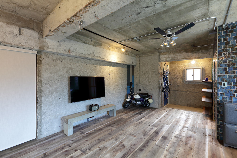Стильный дизайн: открытая гостиная комната в стиле лофт с серыми стенами, паркетным полом среднего тона, телевизором на стене и коричневым полом - последний тренд