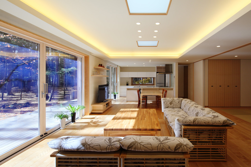 Imagen de salón para visitas abierto de estilo zen de tamaño medio sin chimenea con paredes blancas, suelo de madera clara, televisor independiente y suelo beige