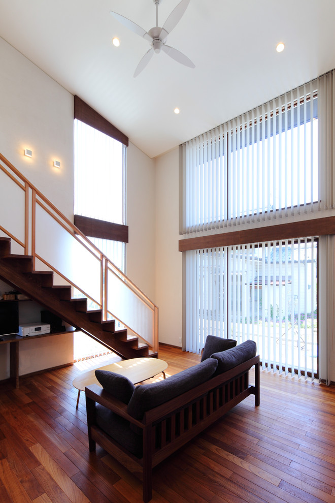Immagine di un soggiorno minimal aperto con pareti bianche, parquet scuro, TV autoportante e pavimento marrone