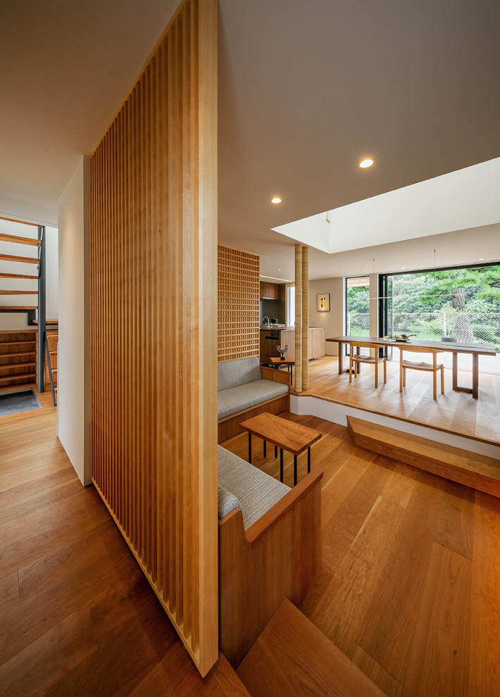 Diseño de salón abierto minimalista grande con suelo de madera en tonos medios, televisor colgado en la pared, machihembrado y ladrillo