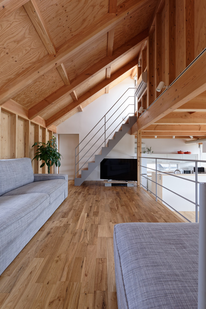 Asiatisches Wohnzimmer im Loft-Stil mit weißer Wandfarbe, braunem Holzboden, freistehendem TV und braunem Boden in Kyoto