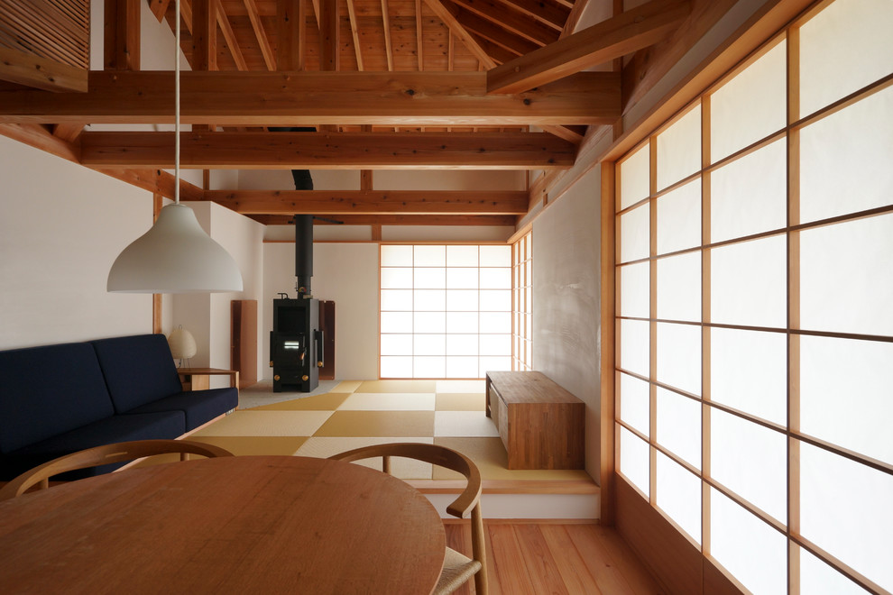 Ejemplo de salón cerrado de estilo zen con paredes blancas, tatami, estufa de leña y marco de chimenea de metal