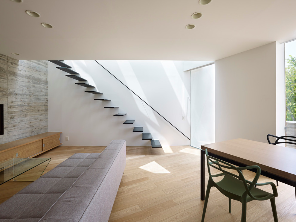 Modernes Wohnzimmer ohne Kamin mit weißer Wandfarbe, hellem Holzboden und freistehendem TV in Sonstige