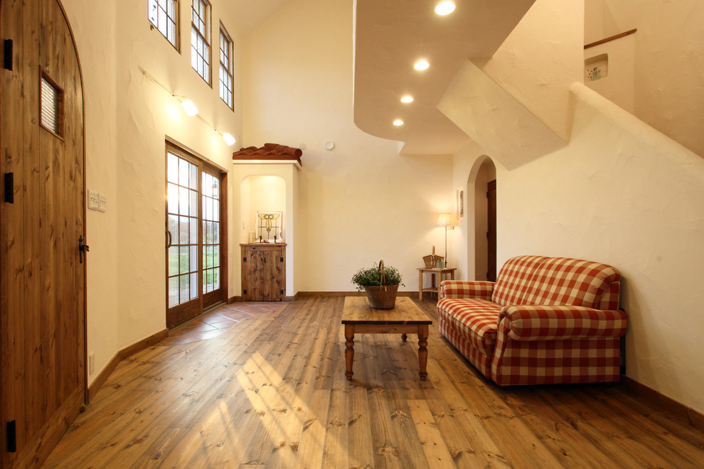 Inredning av ett lantligt vardagsrum, med vita väggar, mellanmörkt trägolv och brunt golv