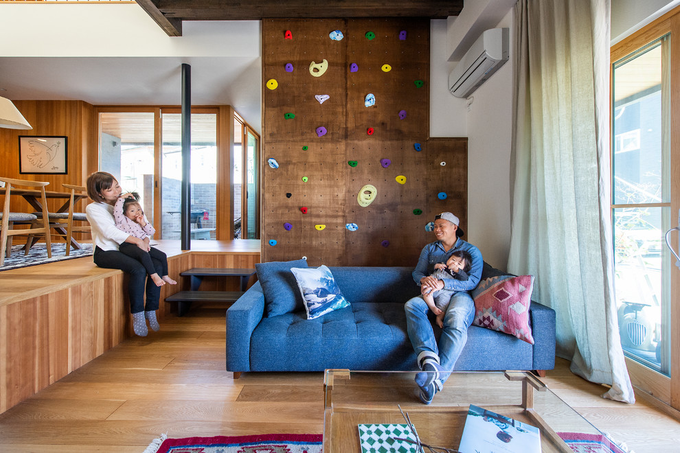 Abgetrenntes Wohnzimmer mit brauner Wandfarbe, hellem Holzboden und freistehendem TV in Kobe