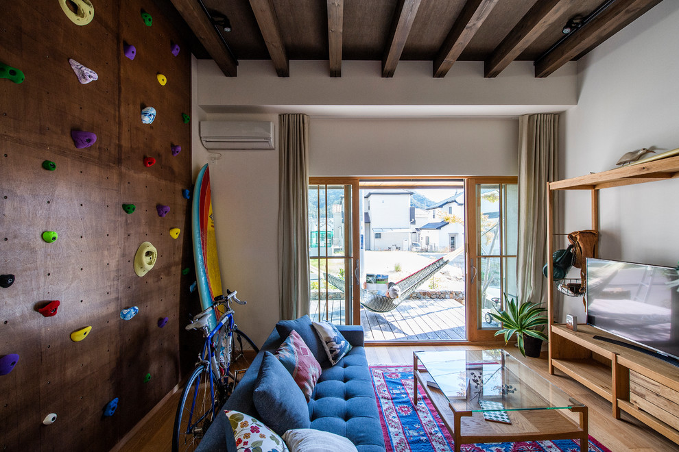 На фото: изолированная гостиная комната в морском стиле с белыми стенами, светлым паркетным полом и отдельно стоящим телевизором с