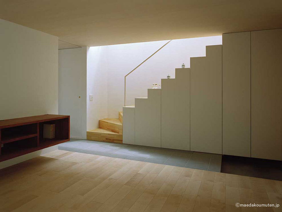 Offenes Wohnzimmer mit weißer Wandfarbe, braunem Holzboden, freistehendem TV, beigem Boden, Holzdecke und Tapetenwänden in Sonstige