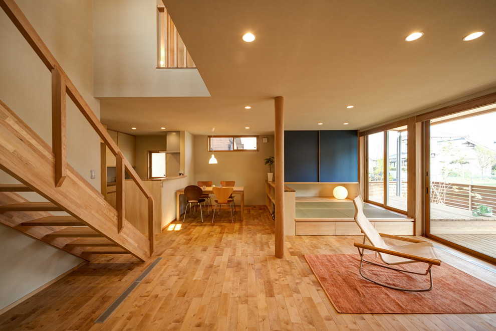 Foto di un grande soggiorno minimalista aperto con pareti beige, parquet chiaro, nessun camino, TV autoportante e pavimento marrone