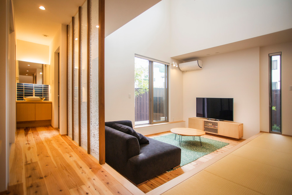 Modelo de salón abierto de estilo zen de tamaño medio sin chimenea con paredes blancas, suelo de madera en tonos medios, televisor independiente y suelo marrón