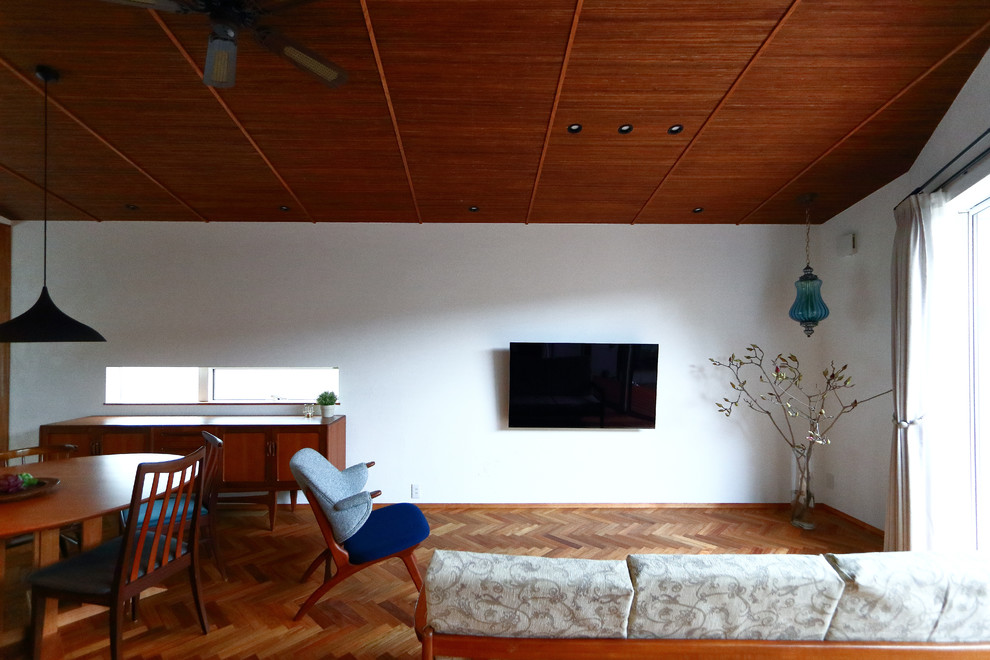 Réalisation d'un salon asiatique de taille moyenne et ouvert avec un mur blanc, un sol en bois brun, un téléviseur fixé au mur et un sol marron.