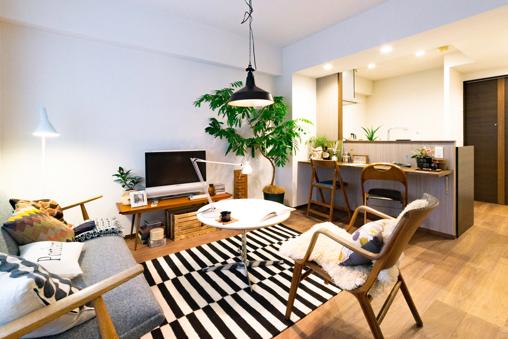 Foto på ett litet minimalistiskt allrum med öppen planlösning, med vita väggar, ljust trägolv, en fristående TV och brunt golv