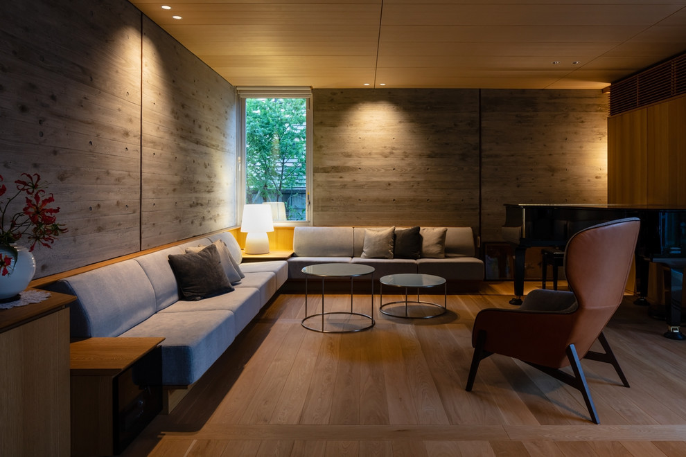 Réalisation d'un salon minimaliste avec un mur gris, un sol en bois brun et un sol marron.