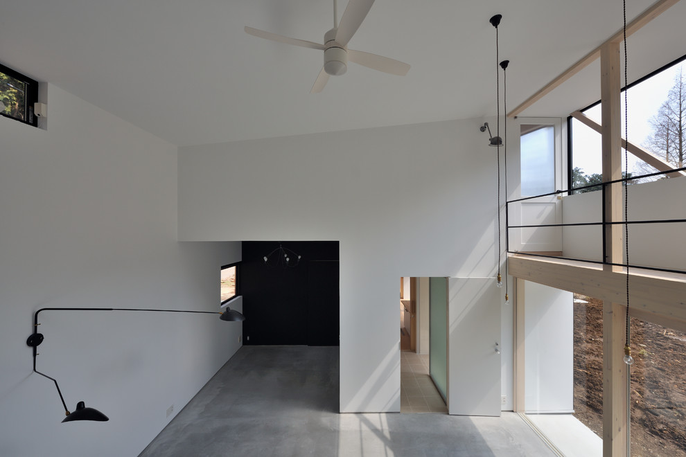 Imagen de salón abierto moderno sin chimenea con paredes blancas, suelo de cemento y suelo gris