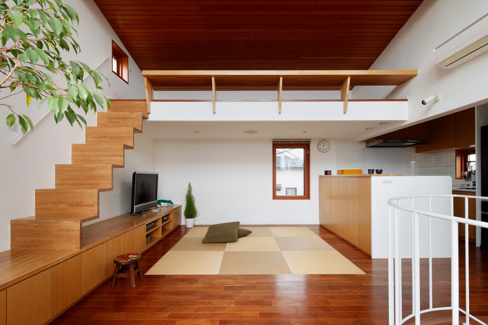 Стильный дизайн: открытая гостиная комната в восточном стиле с белыми стенами, паркетным полом среднего тона и коричневым полом - последний тренд
