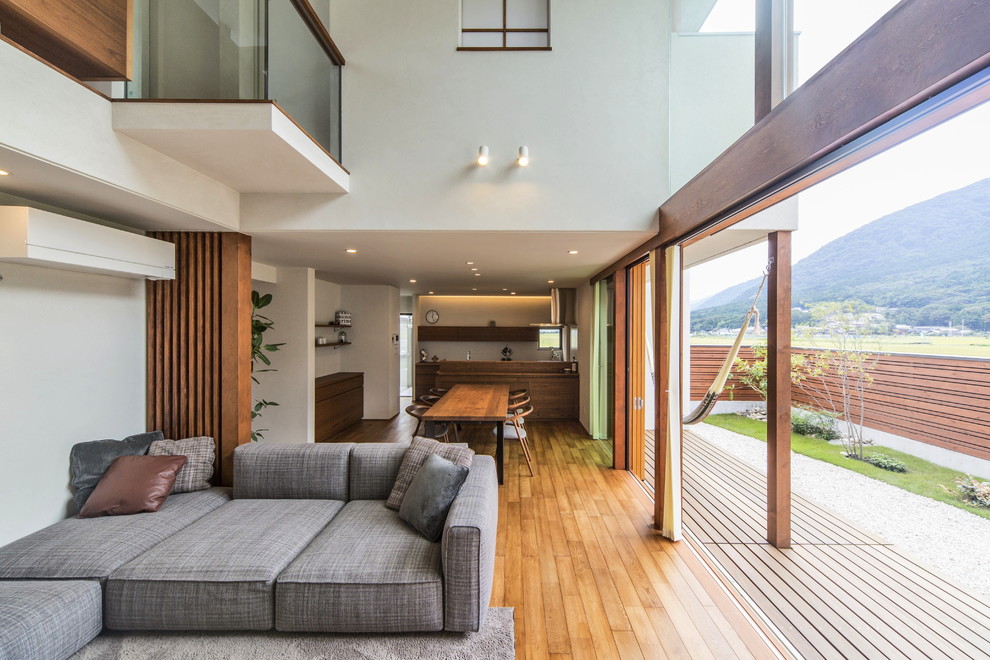 Imagen de salón abierto contemporáneo con paredes blancas, suelo de madera en tonos medios y suelo marrón