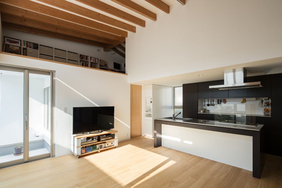 Ejemplo de salón abierto actual con paredes blancas, suelo de madera clara, televisor independiente y suelo marrón