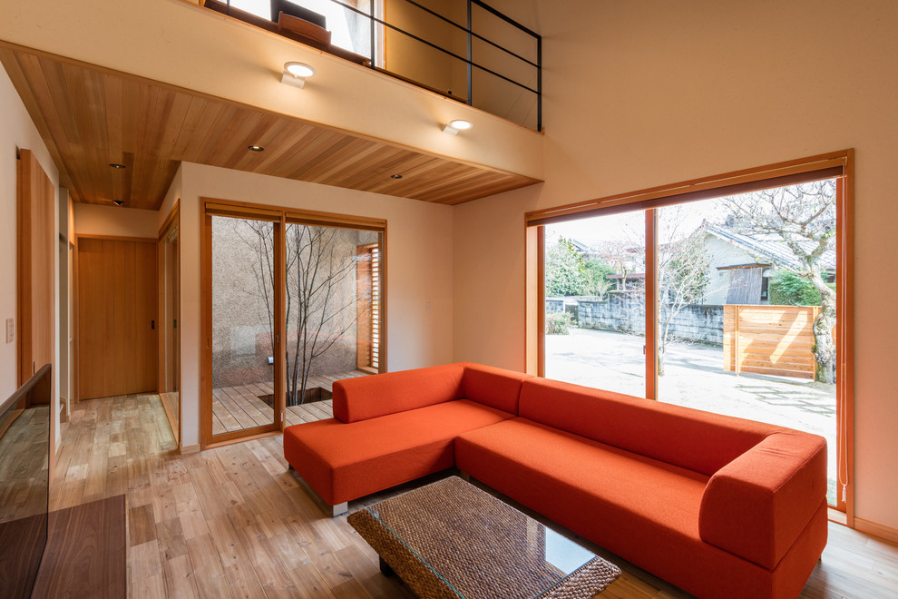Idee per un soggiorno etnico con pareti beige, pavimento in legno massello medio, TV autoportante e pavimento beige
