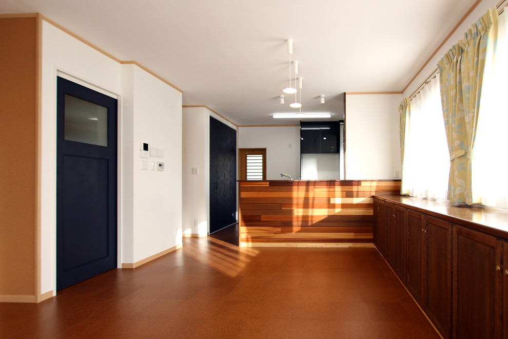 Modern inredning av ett litet allrum med öppen planlösning, med ett finrum, vita väggar, korkgolv och brunt golv