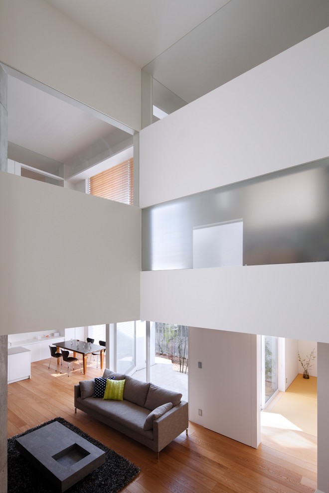 Modelo de salón abierto contemporáneo de tamaño medio con paredes blancas y suelo de madera en tonos medios