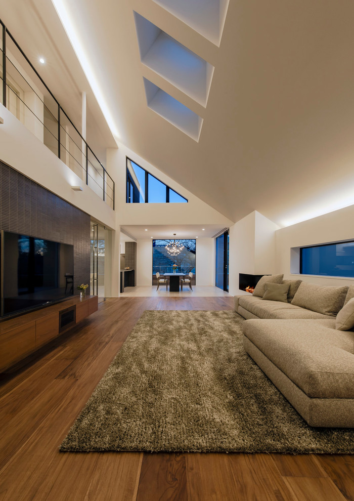 コンテンポラリースタイルのおしゃれな独立型リビング (白い壁、無垢フローリング、横長型暖炉、茶色い床) の写真