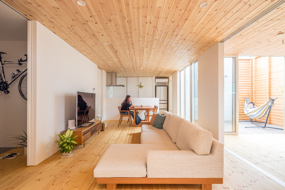 Immagine di un soggiorno etnico aperto e di medie dimensioni con pareti bianche, pavimento in legno massello medio e TV autoportante