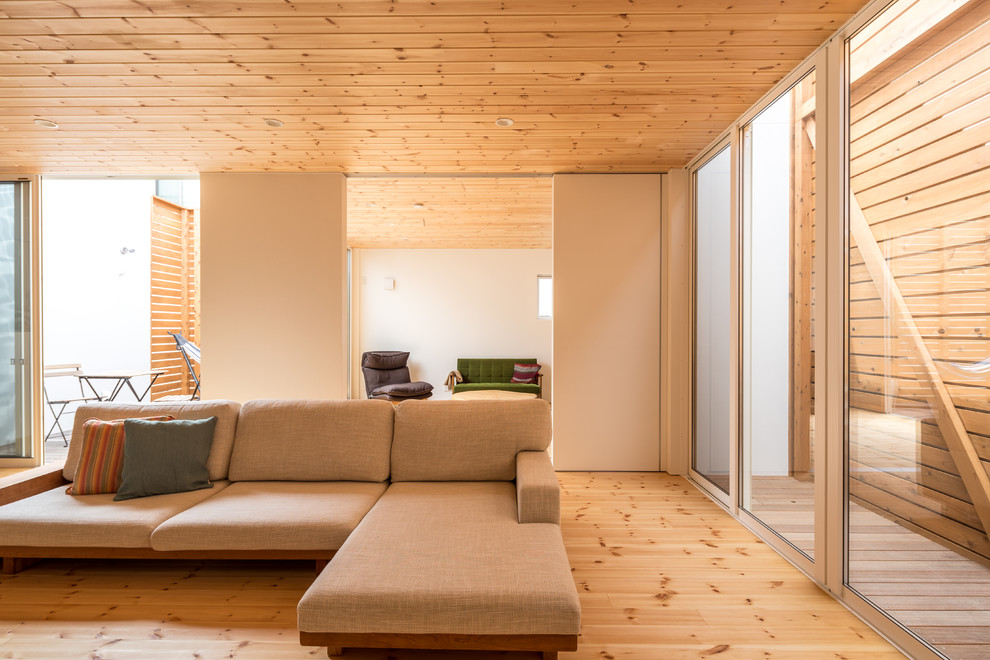 Aménagement d'un grand salon ouvert avec un mur blanc, un sol en bois brun, aucune cheminée et un téléviseur indépendant.