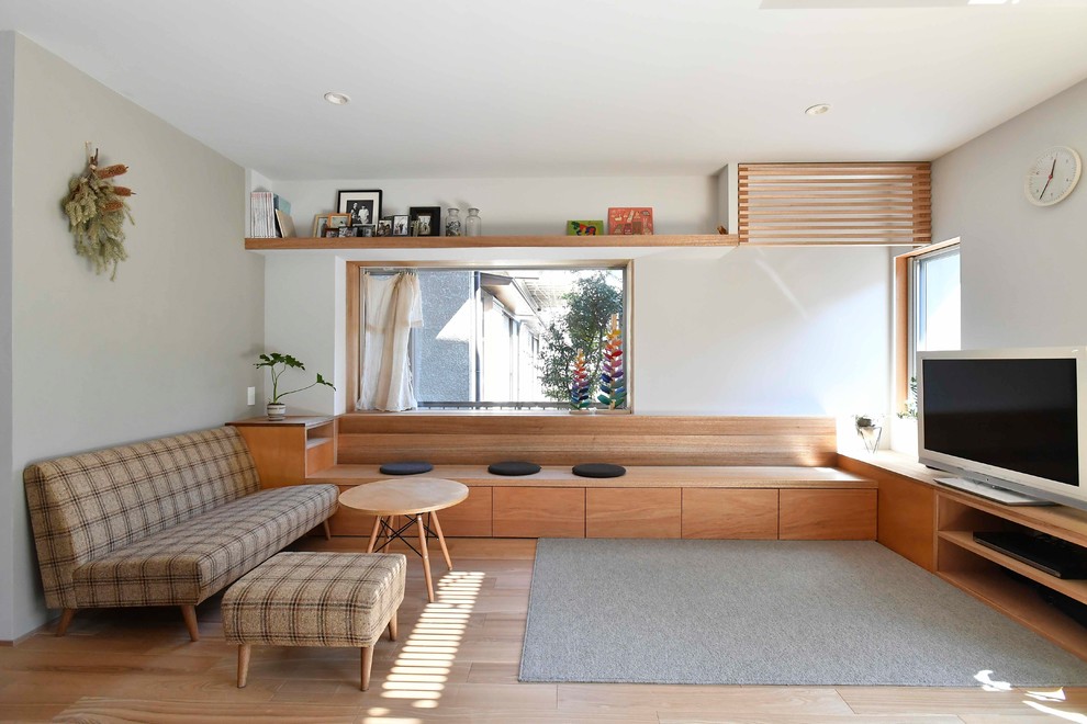 Идея дизайна: гостиная комната в скандинавском стиле с белыми стенами, светлым паркетным полом, отдельно стоящим телевизором и бежевым полом