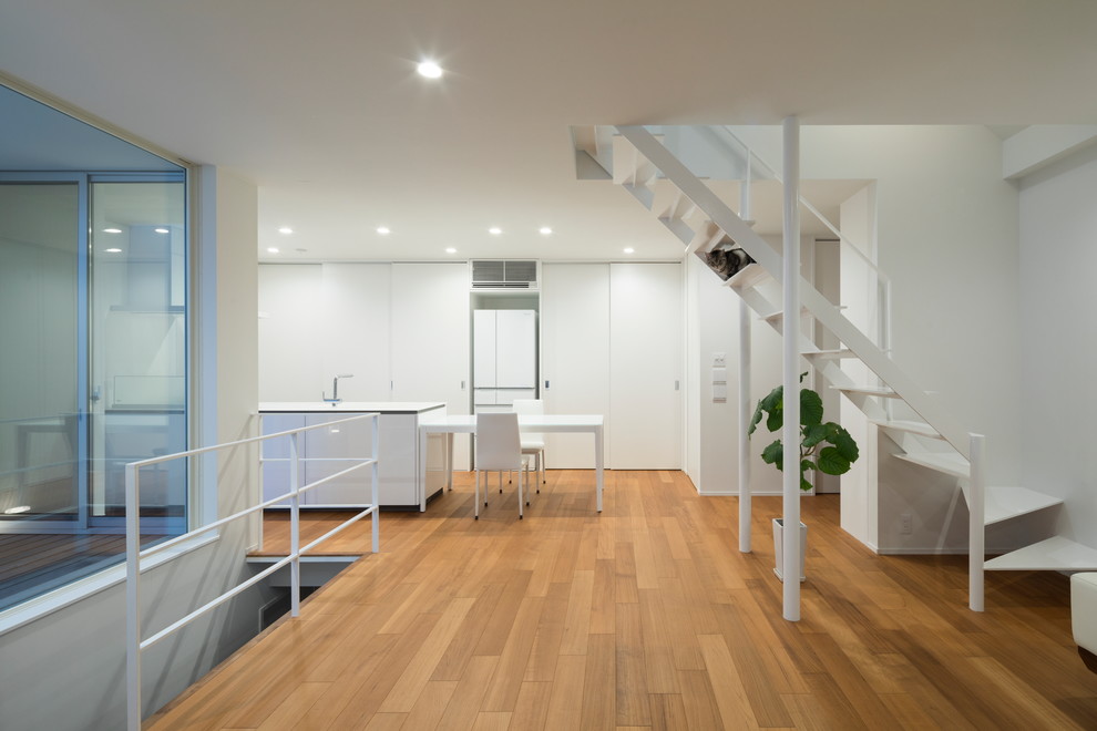 Ispirazione per un soggiorno moderno con pareti bianche, pavimento in legno massello medio e pavimento marrone