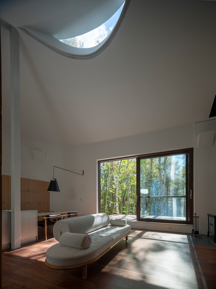 Imagen de salón abierto minimalista con paredes blancas, suelo de contrachapado, estufa de leña y marco de chimenea de yeso