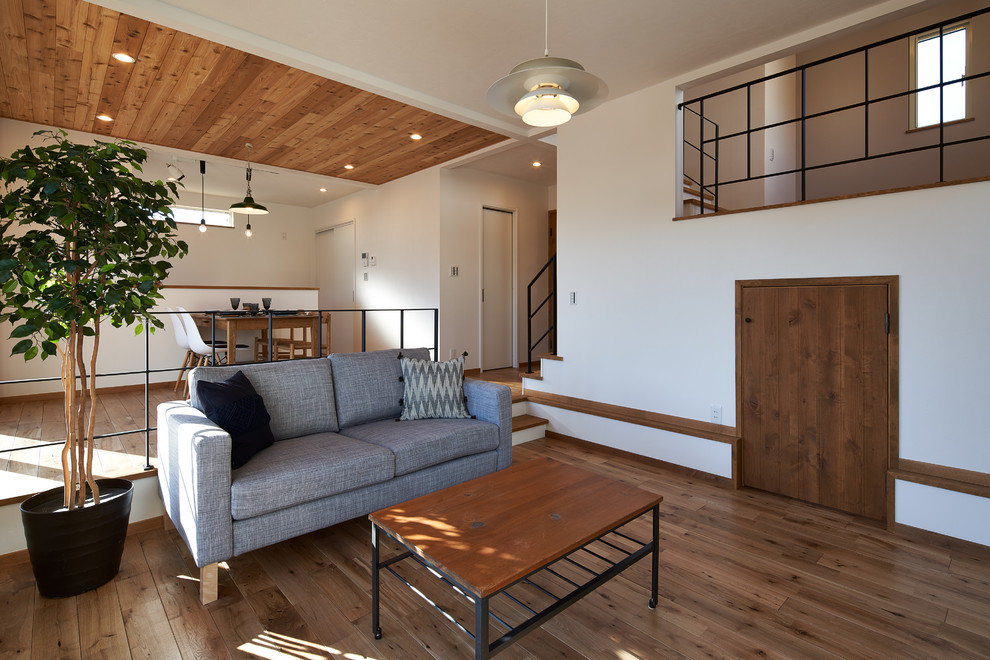 Mittelgroßes, Offenes Country Wohnzimmer mit weißer Wandfarbe, braunem Holzboden und braunem Boden in Sonstige