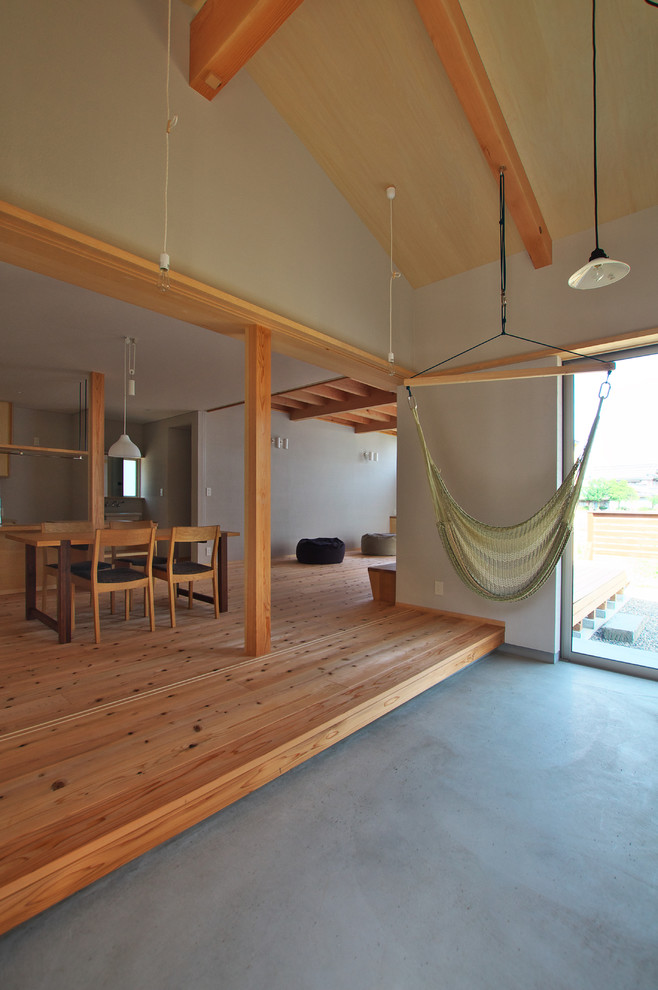 Aménagement d'un salon asiatique ouvert avec un mur beige, un sol en bois brun et aucune cheminée.