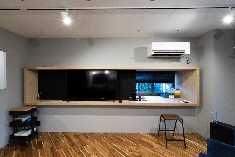 Mittelgroßes, Repräsentatives, Offenes Industrial Wohnzimmer ohne Kamin mit grauer Wandfarbe, freistehendem TV und braunem Boden in Tokio