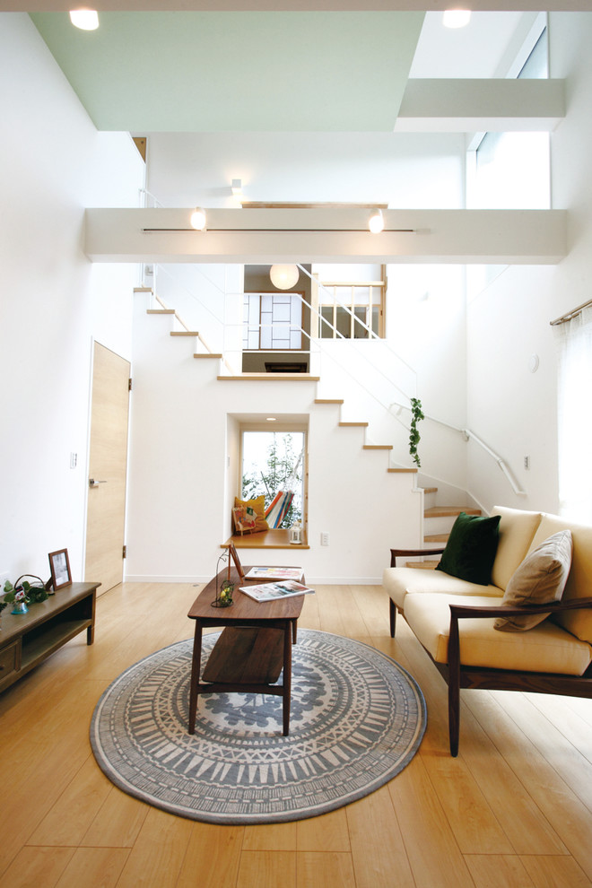 Offenes Skandinavisches Wohnzimmer mit weißer Wandfarbe, Sperrholzboden und beigem Boden in Sonstige