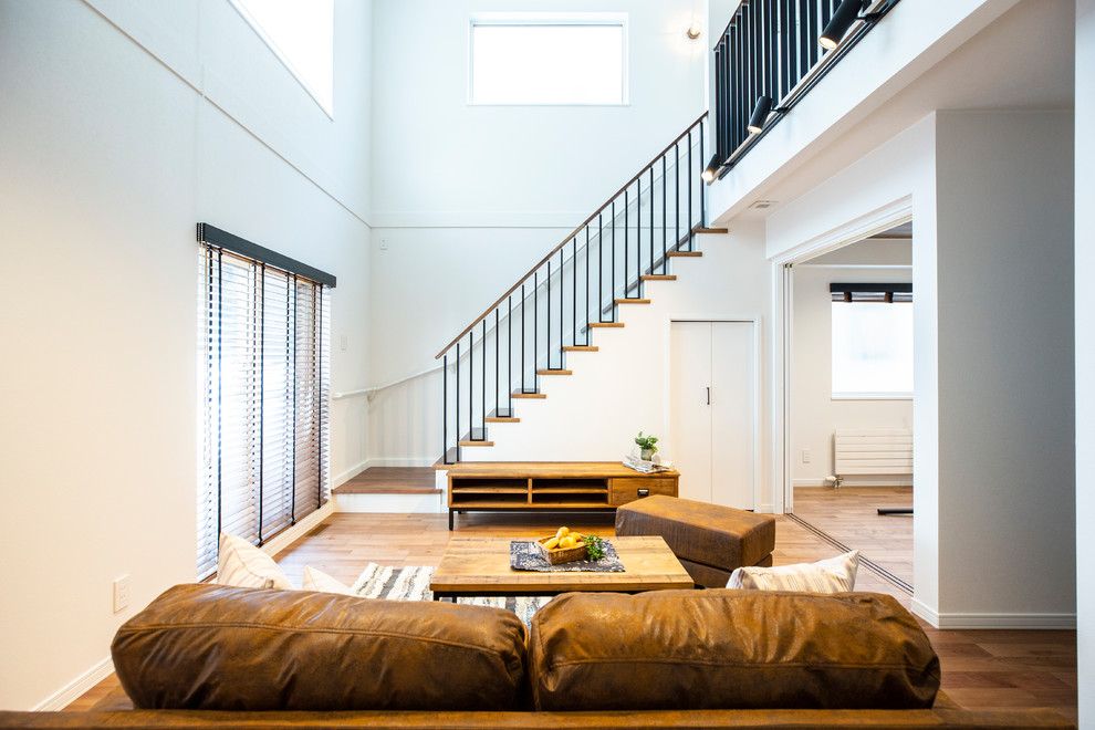 Fernseherloses Industrial Wohnzimmer ohne Kamin mit weißer Wandfarbe, braunem Holzboden und braunem Boden in Sapporo