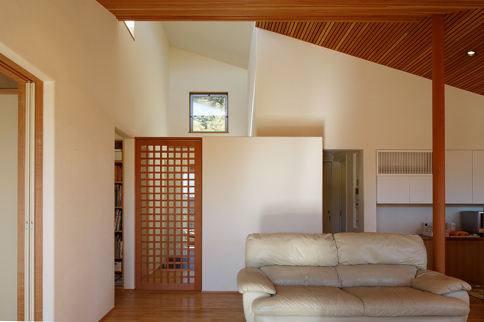 Ejemplo de salón abierto de estilo zen de tamaño medio sin chimenea con paredes blancas, suelo de madera en tonos medios, televisor independiente y suelo marrón