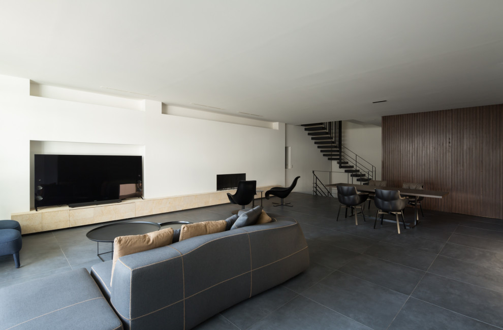 Foto på ett funkis allrum med öppen planlösning, med vita väggar, en fristående TV och grått golv
